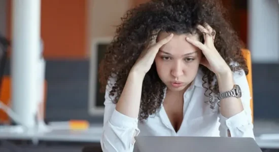 Como lidar com a pressão durante a pós-graduação EaD? | Mulher na frente do notebook com uma expressão de exausta | FAVENI