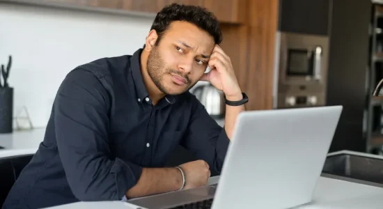 Como o curso de pós-graduação EaD ajuda a mudar de carreira? | Foto de homem indiano em frente ao notebook com uma expressão triste | FAVENI