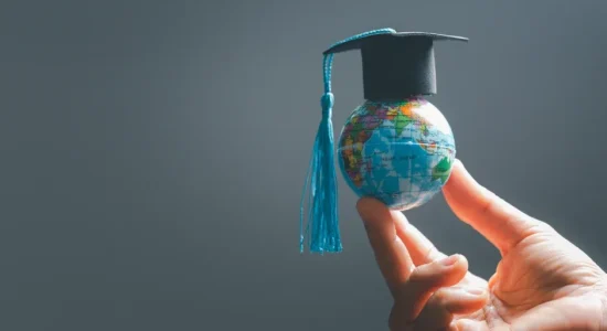 Curso EaD oferece diploma com reconhecimento internacional? | Uma mão segurando um globo com um capelo | FAVENI
