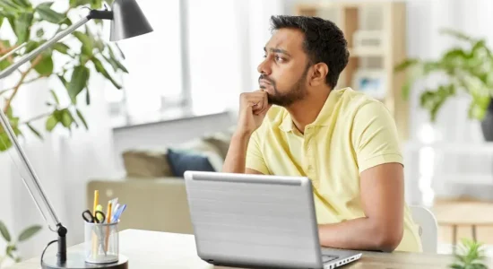Me formei, e agora? Saiba o que fazer depois da faculdade! | Foto de um homem indiano com expressão pensativa usando o notebook | FAVENI