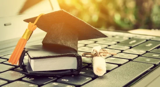 Por que fazer uma pós EaD na FAVENI? | Foto de um notebook com um mini capelo e um mini diploma sobre o teclado | FAVENI
