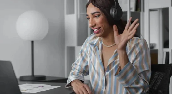 Pós-graduação ideal: como fazer a escolha certa? | Foto de mulher sorrindo usando fones de ouvidos enquanto faz uma reunião no notebook | FAVENI