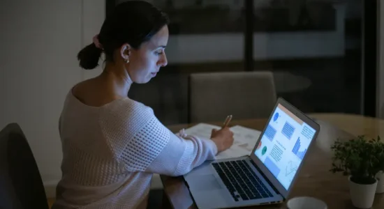 Pós-graduação online: 6 motivos para investir nesse curso | Foto de mulher em casa estudando online a noite | FAVENI