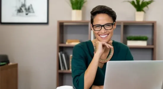 Qual é o papel da pós EaD na requalificação profissional? | Foto de mulher sorrindo para câmera com notebook em sua frente | FAVENI
