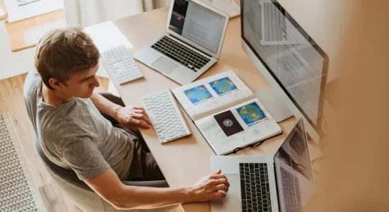 Vantagens da pós EAD no mercado de trabalho | Homem usando 3 computadores | FAVENI