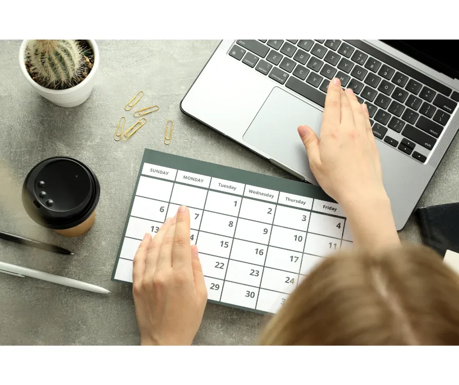 Curso de pós-graduação EaD: qual é a carga horária? | Foto superior de uma mulher mexendo no notebook e olhando um calendário | FAVENI