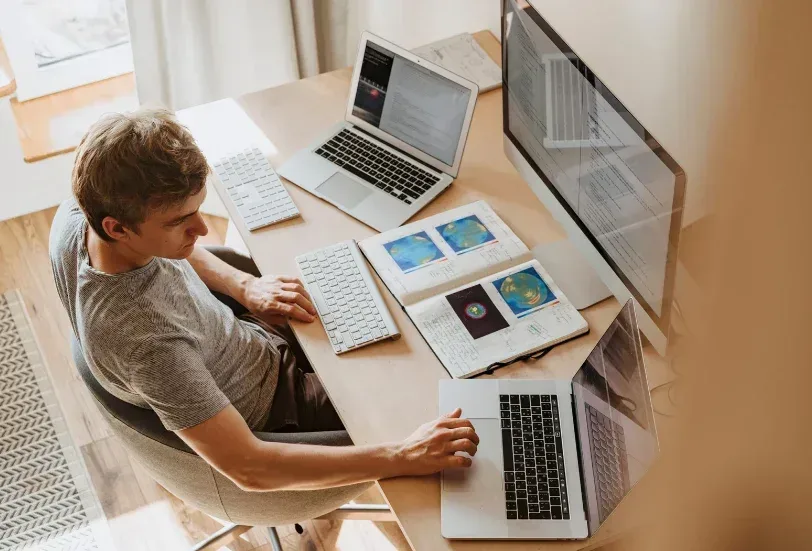 Vantagens da pós EAD no mercado de trabalho | Homem usando 3 computadores | FAVENI